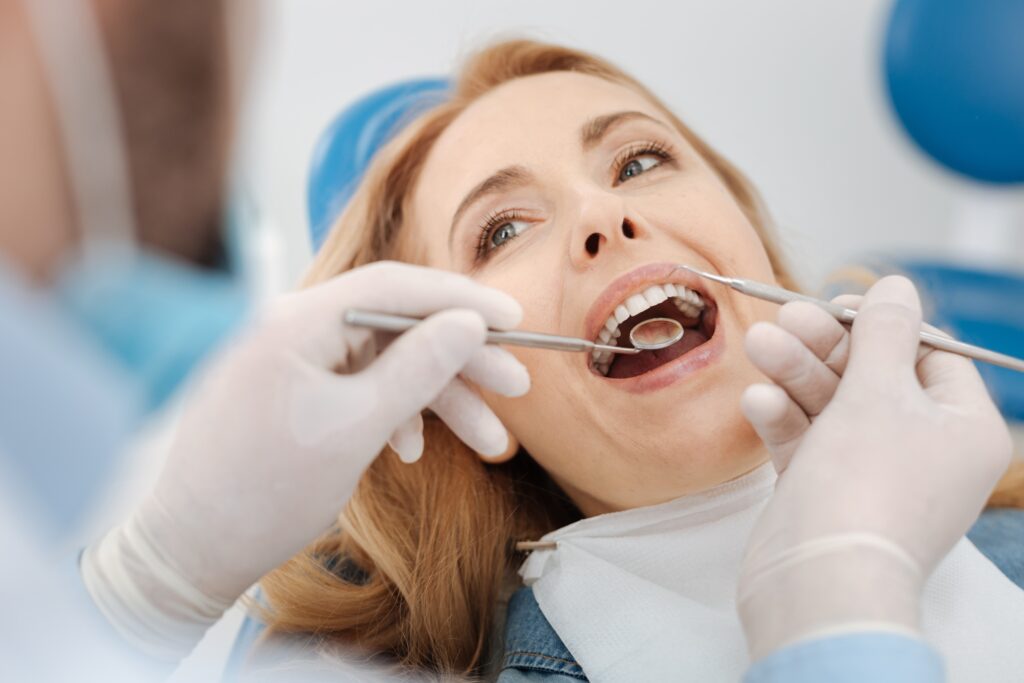 Smiling woman in dental chair receive dental cleaning during a routine dental cleaning and exam appointment