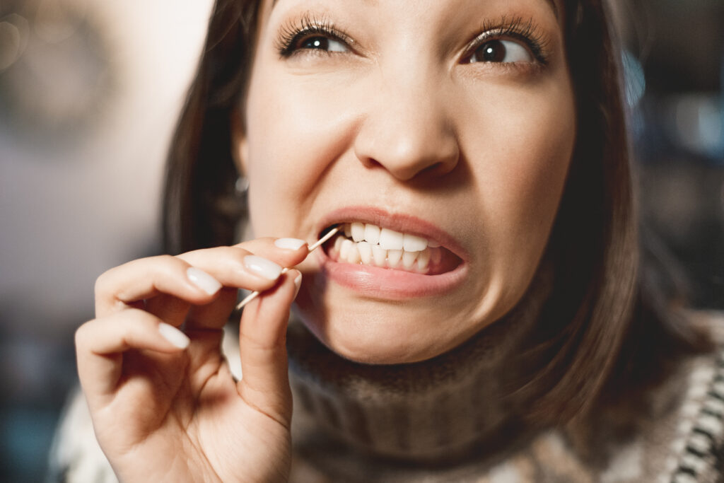 woman picking food stuck between her teeth