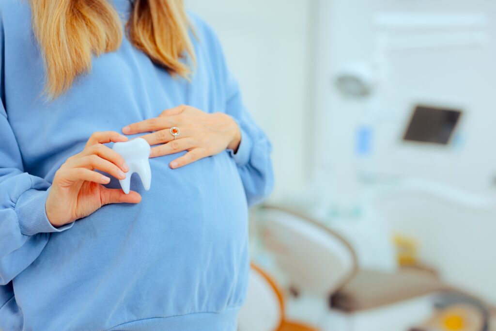 pregnant woman holding tooth concerned for her oral health during pregnancy